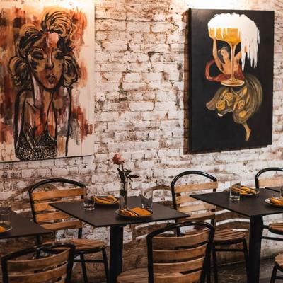 Restaurant dining area with set tables, chairs and art on the wall.