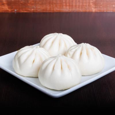 Four pork buns on a white plate.