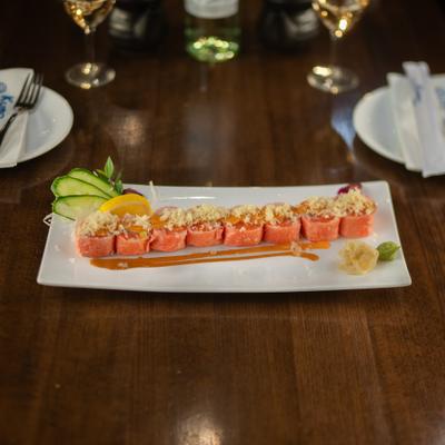 Tricolor sushi roll served with wasabi, pickled ginger, and cucumber garnish on a rectangular plate.