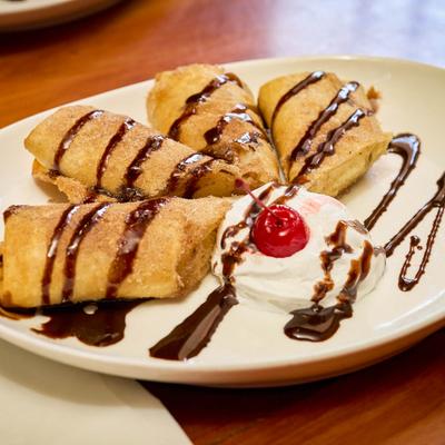Chocolate drizzled dessert rolls served with a cherry.