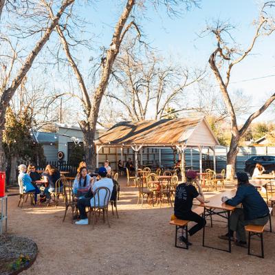 People seated at tables on a sunlit courtyard.