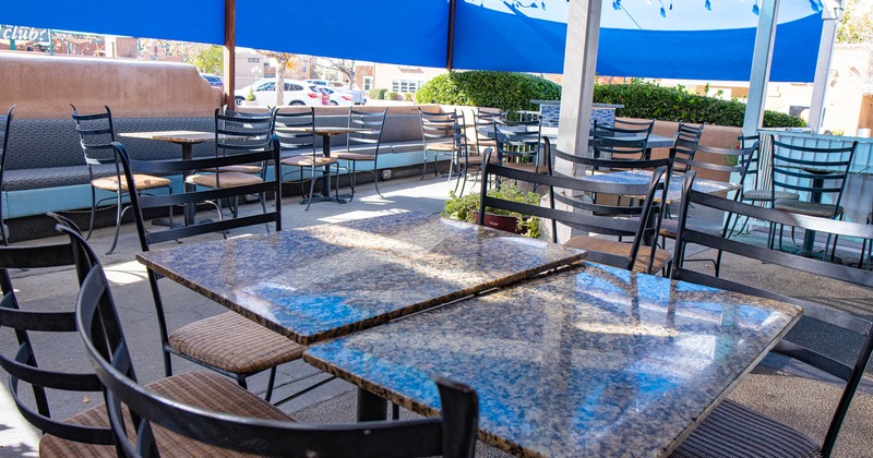 Exterior covered seating area, tables, chairs, plants, parked cars