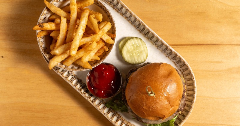 Burger accompanied by fries, ketchup, and pickles