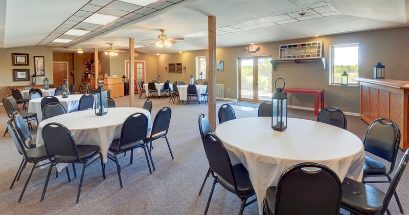 Interior, spacious room with round tables, metal table lanterns and chairs