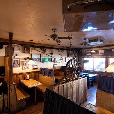 Interior featuring wooden booths, wall art, and a decorative ship wheel.
