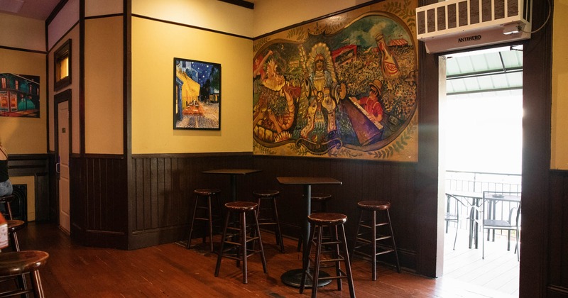 Seating area, two tables with bar stools, wall with painting decoration