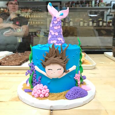 Mermaid cake with blue icing, purple tail, and playful sea-themed decorations.
