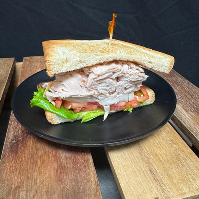 Half turkey sandwich on white with lettuce tomato and onion.