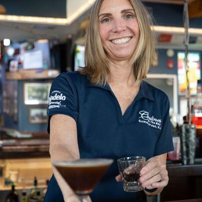 A friendly bartender serves Espresso Martini on a bar counter.