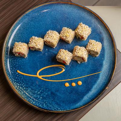 Sushi rolls topped with small crispy pearls on a blue plate.