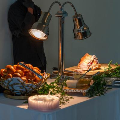 Buffet carving station table with lamp, a board with meat, condiments, and a bread basket.