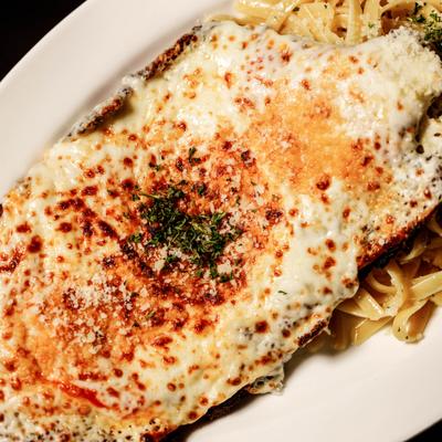 Chicken Parmigiana topped with metled cheese and served with Fettuccini Oleo.