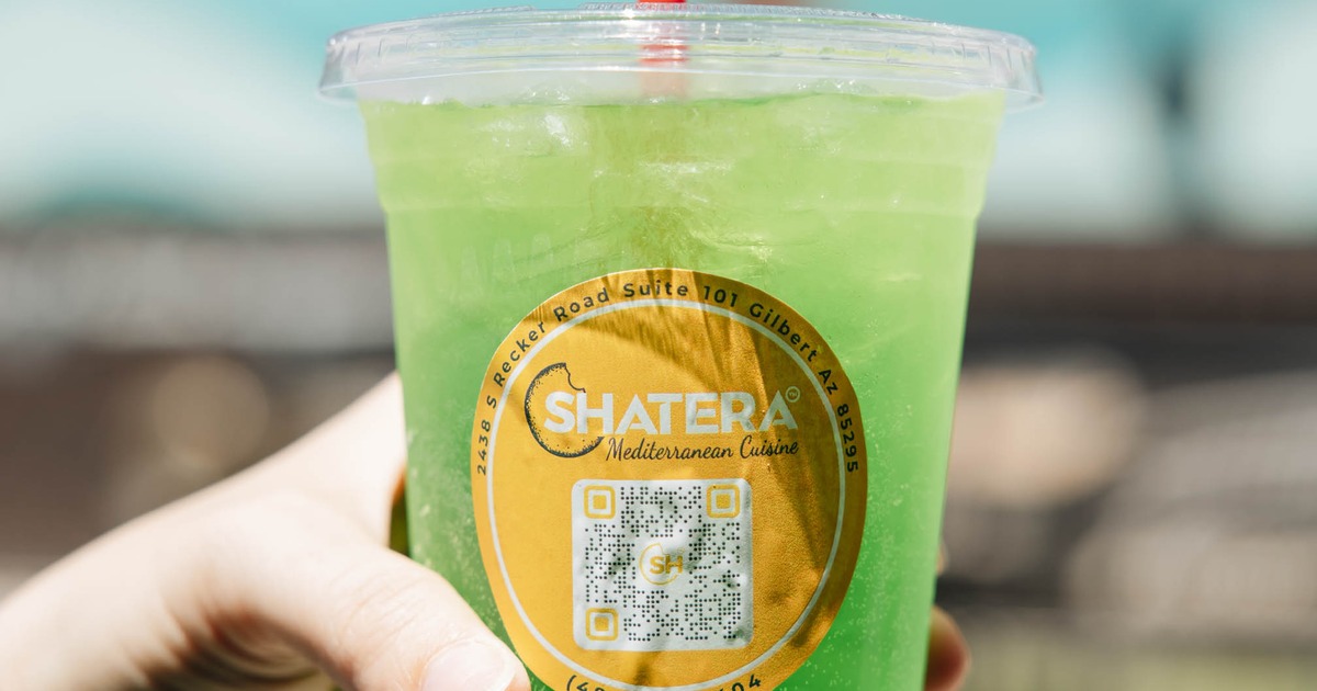Green iced drink in a plastic cup with a lid and a straw