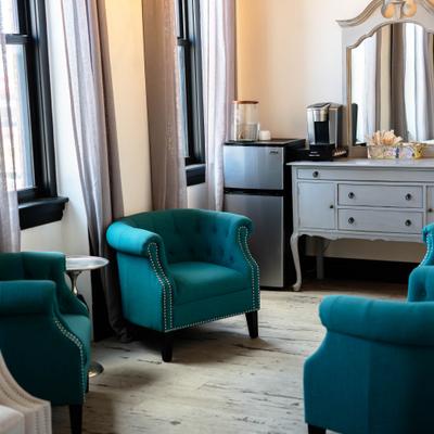 Teal armchairs sit in a room with a grey vanity.