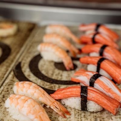 Shrimp and imitation crab nigiri sushi arranged on a textured platter.