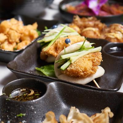 Bao bun plate surrounded by various dishes, close up.