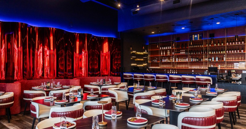 Interior - red and blue accents, plush seating, tables, red and white settings; a well-stocked bar