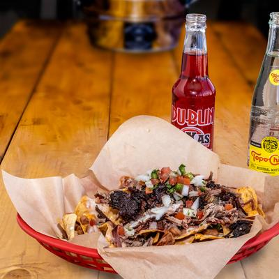Brisket nachos and soft drinks on table.