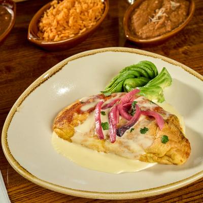 Bacon Omlette topped with sauce and pickled onions, served with sliced avocado.