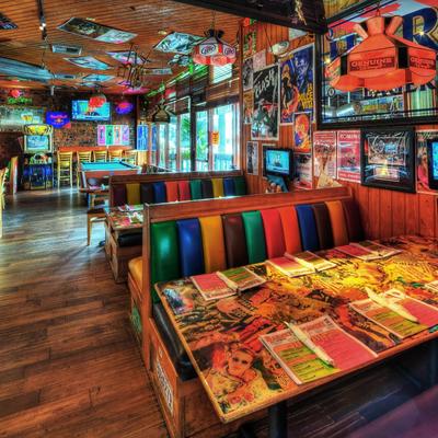 Retro-themed diner with vibrant, multicolored booth seating and collage-covered tables