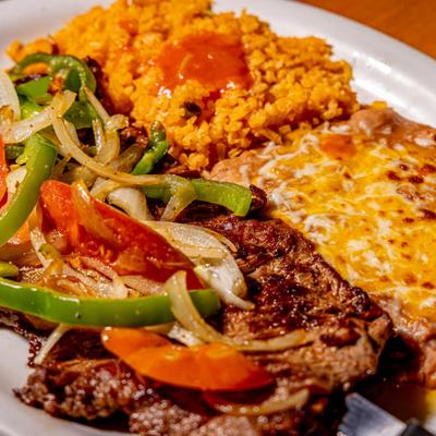 Steak with grilled onions, peppers, tomatoes, rice, and refried beans.