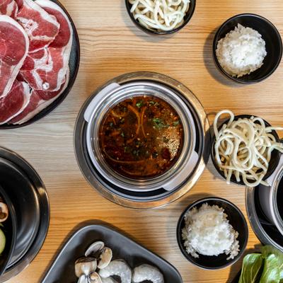 Broth with spices alongside noodle and white rice cups.
