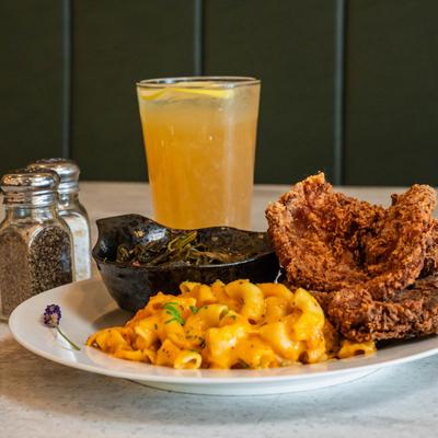Southern-fried pork chops with mac and cheese and collard greens, served with a drink.