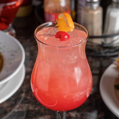 Pink cocktail with cherry and orange slice garnish.