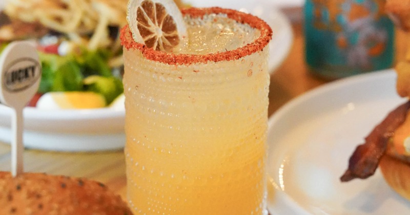 Citrus cocktail beside a burger and salad
