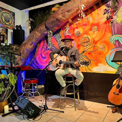 A musician on the stage playing the guitar and singing.