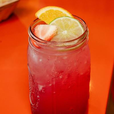 Limonada frutos rojos with citrus slices.
