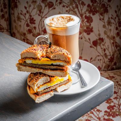 Breakfast bagel sandwich served with a foamy latte.