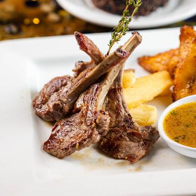 Grilled lamb chops with fried plantains on a plate.