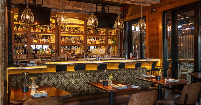 Interior, bar with stools in the back, seating are in the front, banquette bench with tables