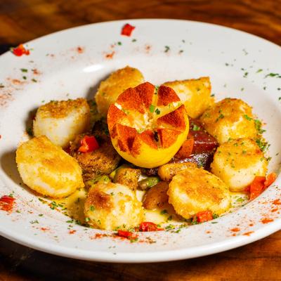 Scallops Scampi topped with drawn butter and garnished with Cajun vegetables.