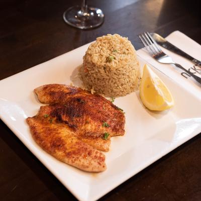 Fish filet with rice and lemon wedge.
