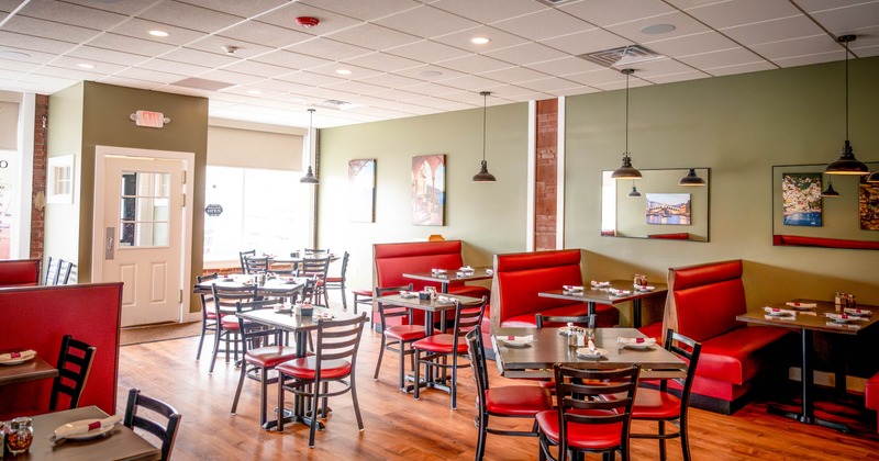 Interior - red cushioned chairs, booths, wooden flooring; green walls decorated with framed photos