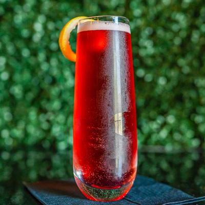 Apple of My Eye cocktail, red colored, garnished with lemon.