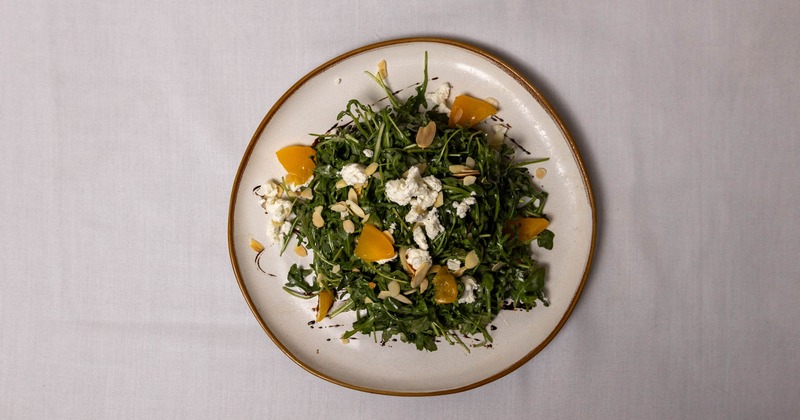 Top-down view of arugula salad with almonds and goat cheese