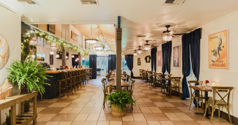 Interior with tilled flor, bar area with a counter, seating area and hanging chandeliers