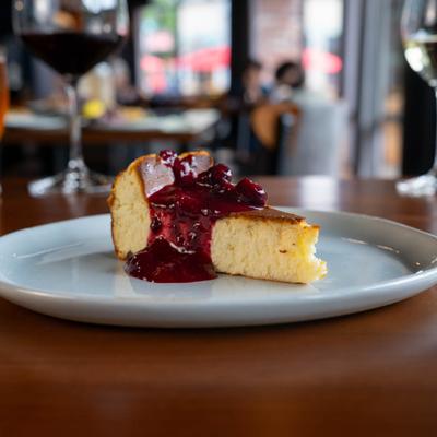 Basque Cheesecake on a white plate, with blurred glass of wine in the background.