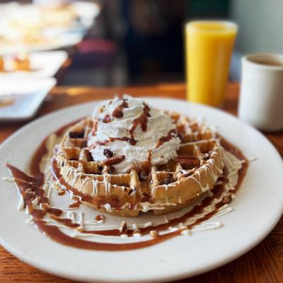 Cinnamon Roll Waffle plate on a table, orange juice and white mug in the background.