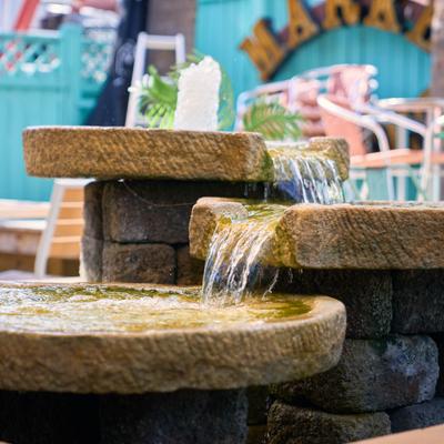 Stone fountain flowing in an outdoor patio seating area.
