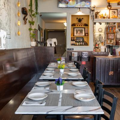 Interior with set tables, wooden bench, chairs, counter area and various decorations.