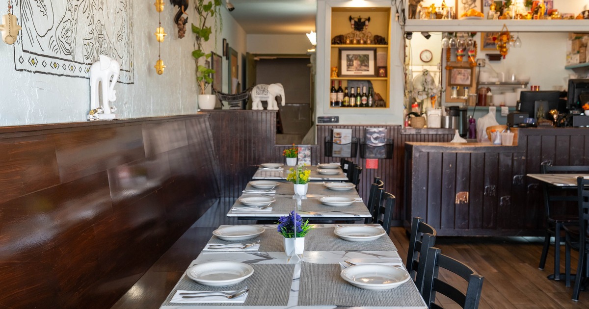 Interior - tables set with dishes and flowers, dark wood bench along the wall; a decorative bar area