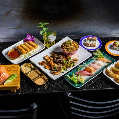 Spread including sashimi, sushi rolls, nigiri, spring rolls, gyoza, and hibachi.