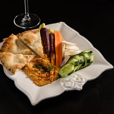 Hummus with vegetables, cheese, and pita bread.