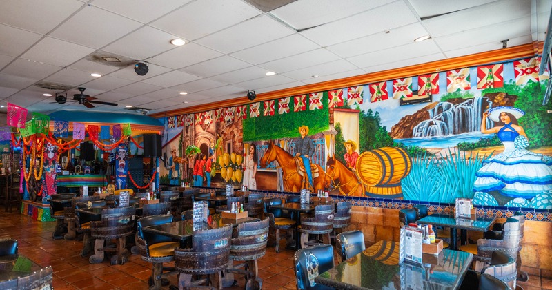 Interior of a restaurant with vibrant Mexican mural and colorful festive decor