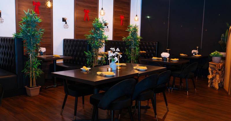 Interior, elegant dining area with plants, wooden tables and chairs