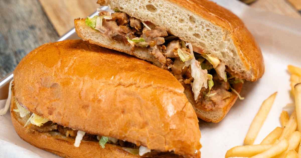 Mexican torta sandwich filled with meat and served with fries on the side